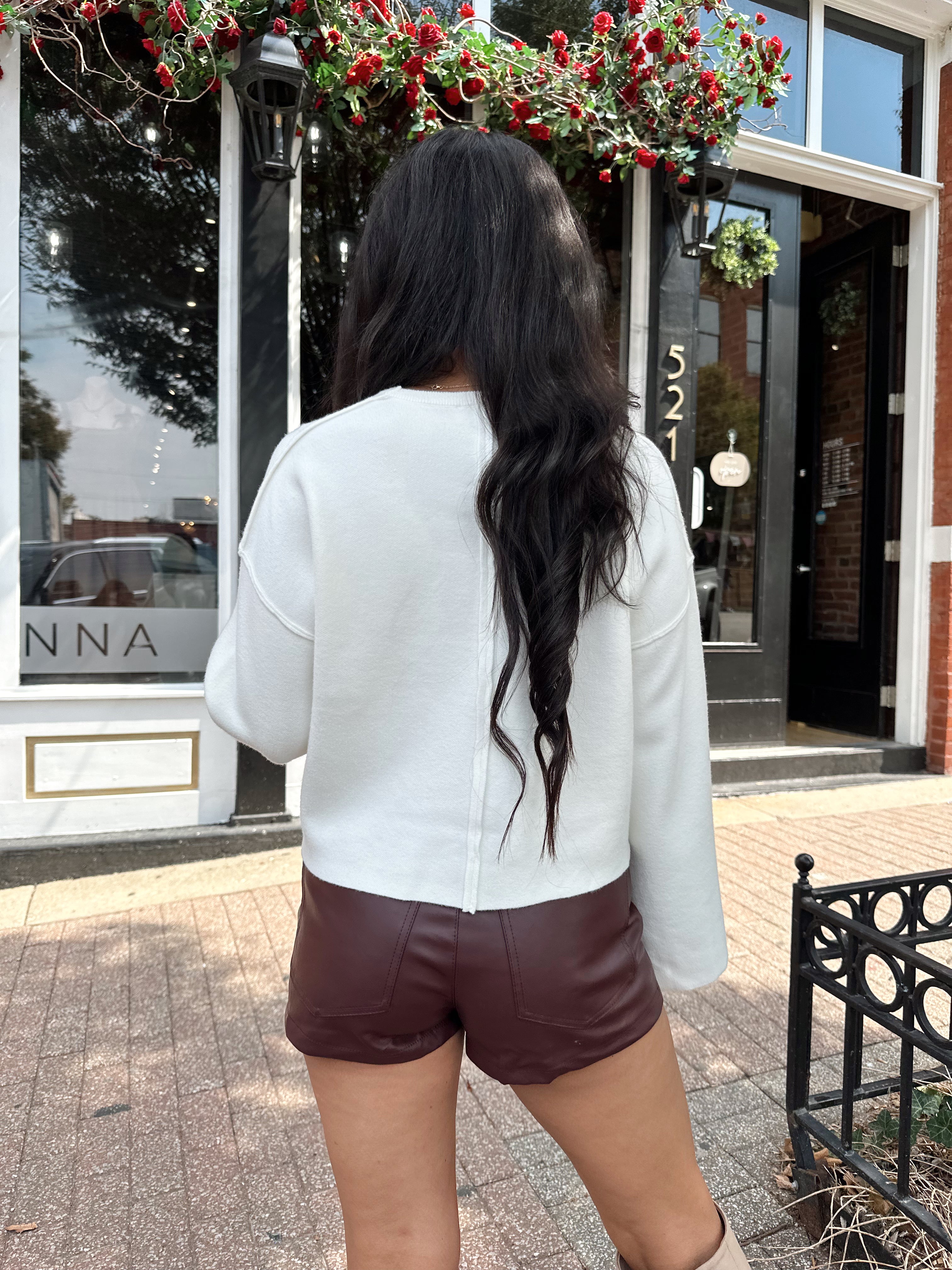Woman wearing burgundy leather short with functional pockets and white top.