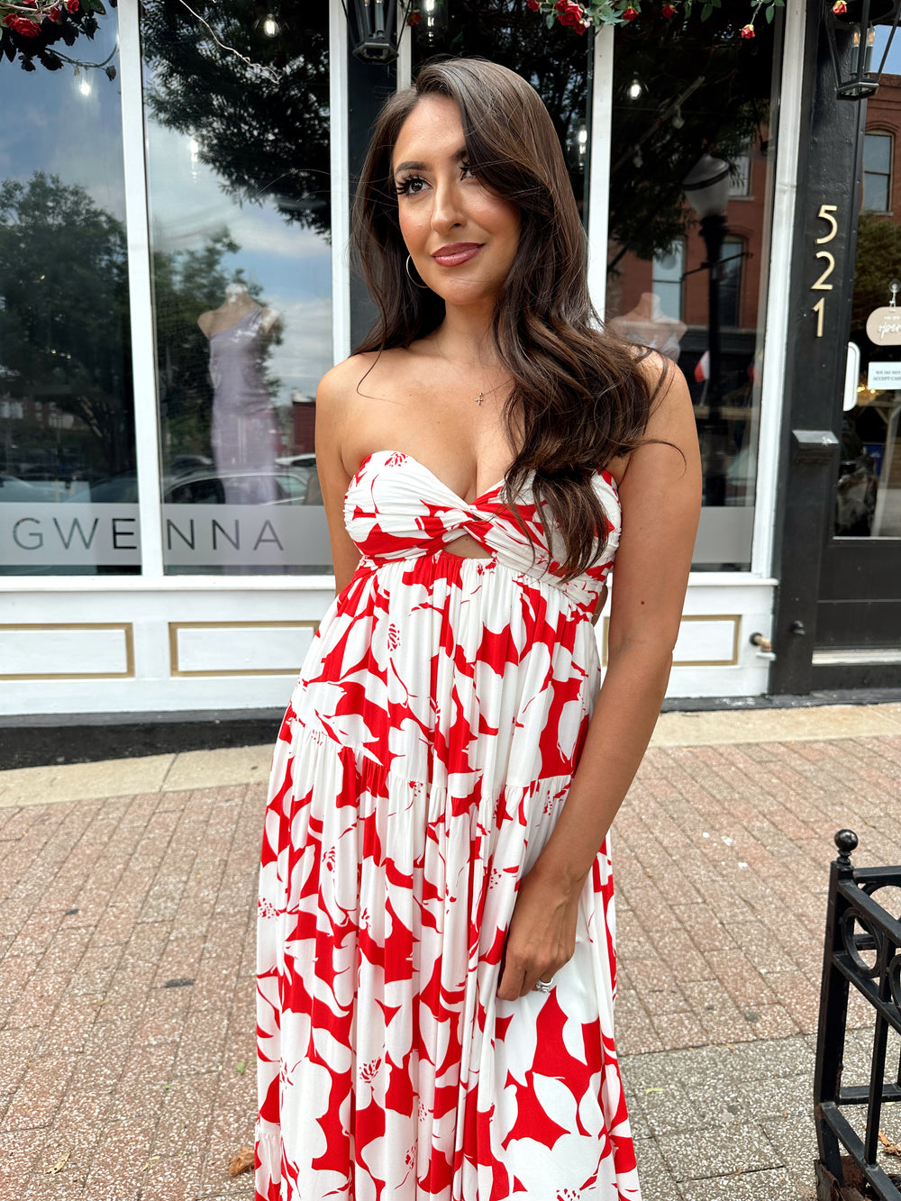 Woman wearing a sleeveless red and white floral mai dress with open back and elastic strap.