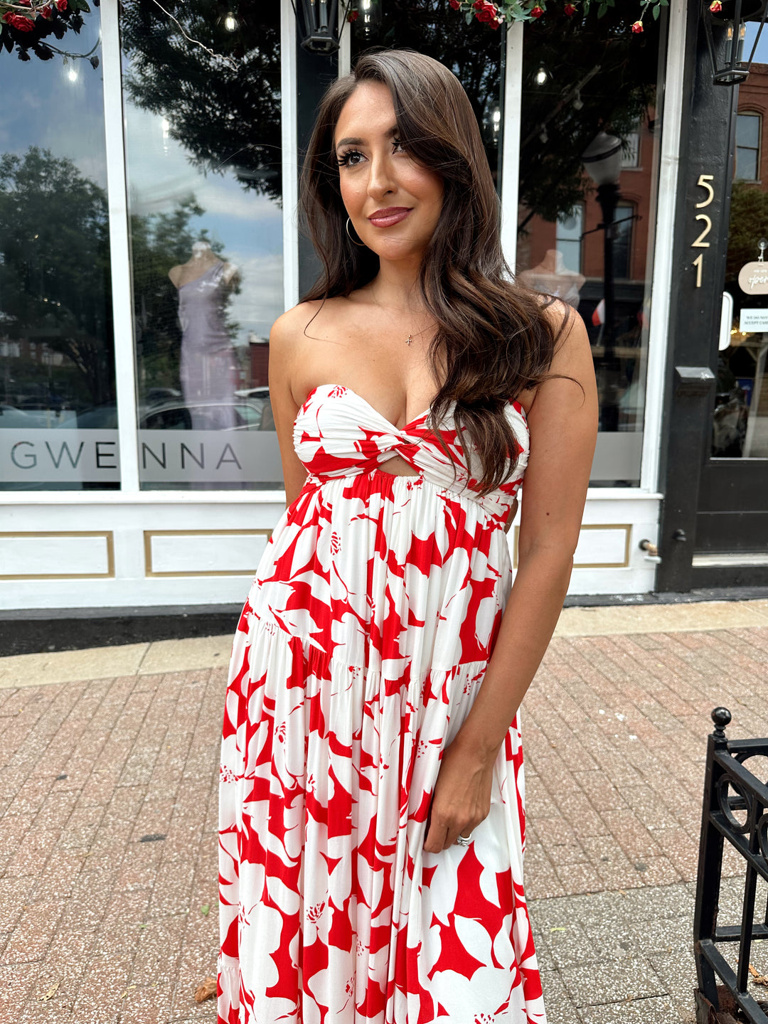 Woman wearing a sleeveless red and white floral mai dress with open back and elastic strap.