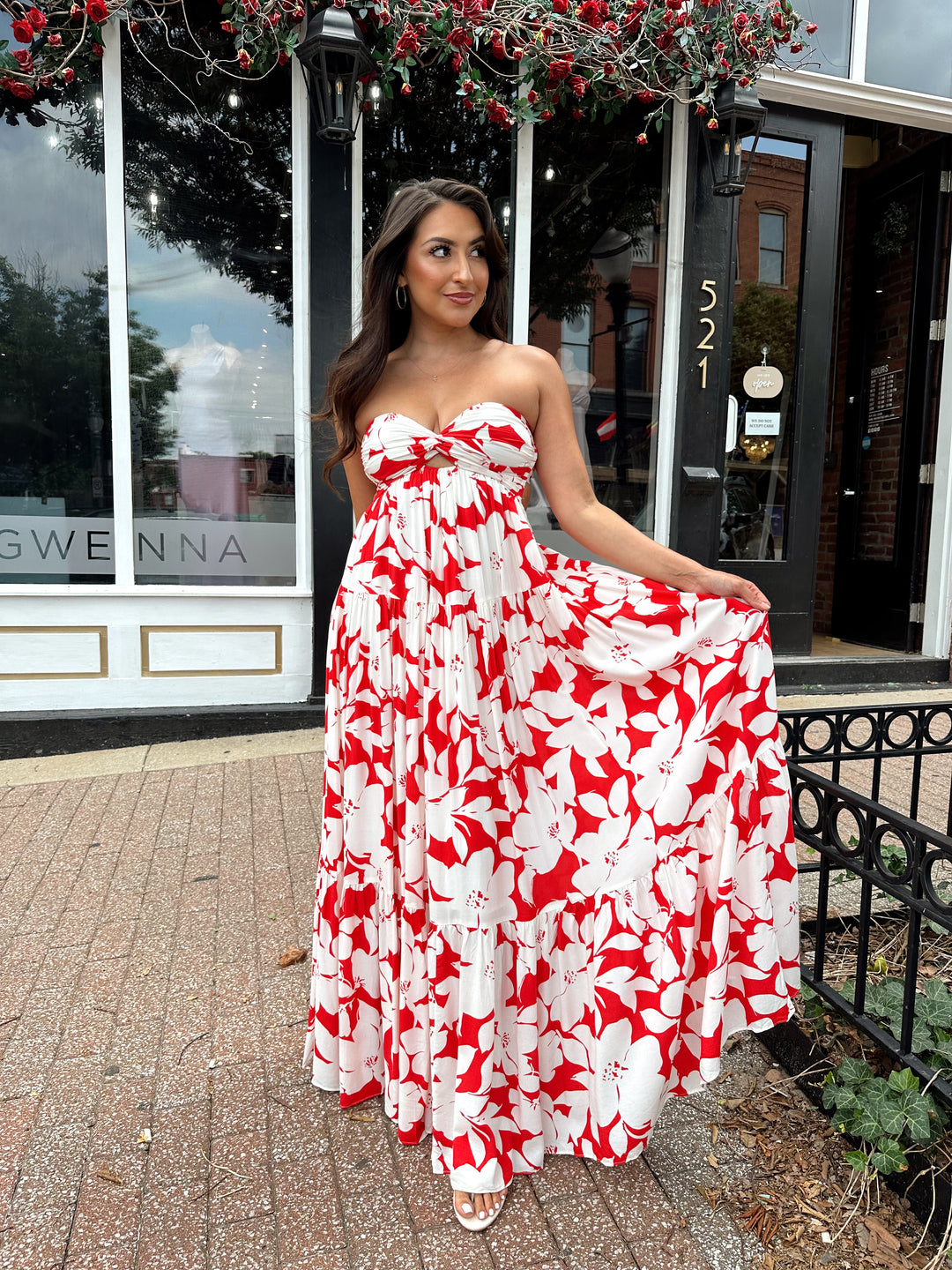 Woman wearing a sleeveless red and white floral mai dress with open back and elastic strap.