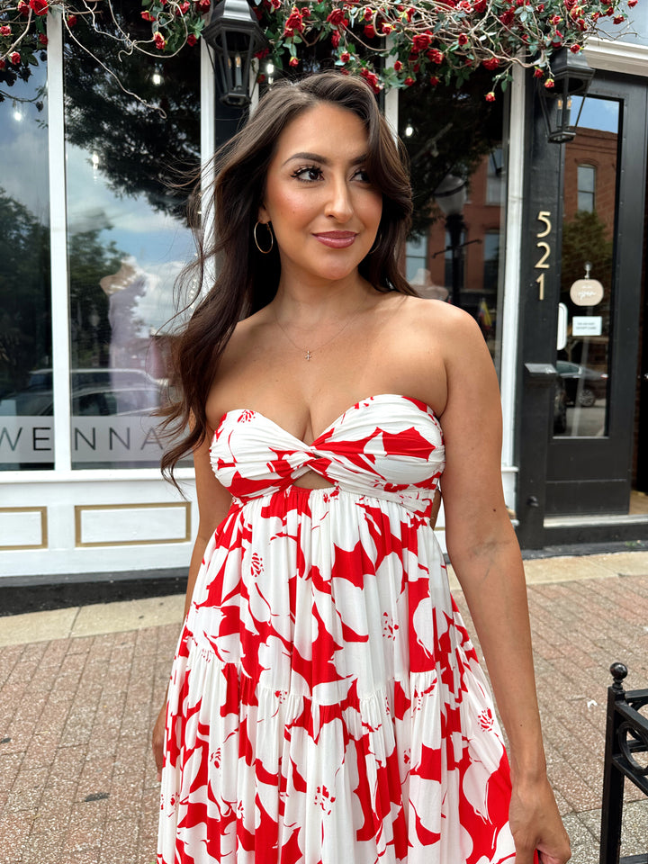 Woman wearing a sleeveless red and white floral mai dress with open back and elastic strap.
