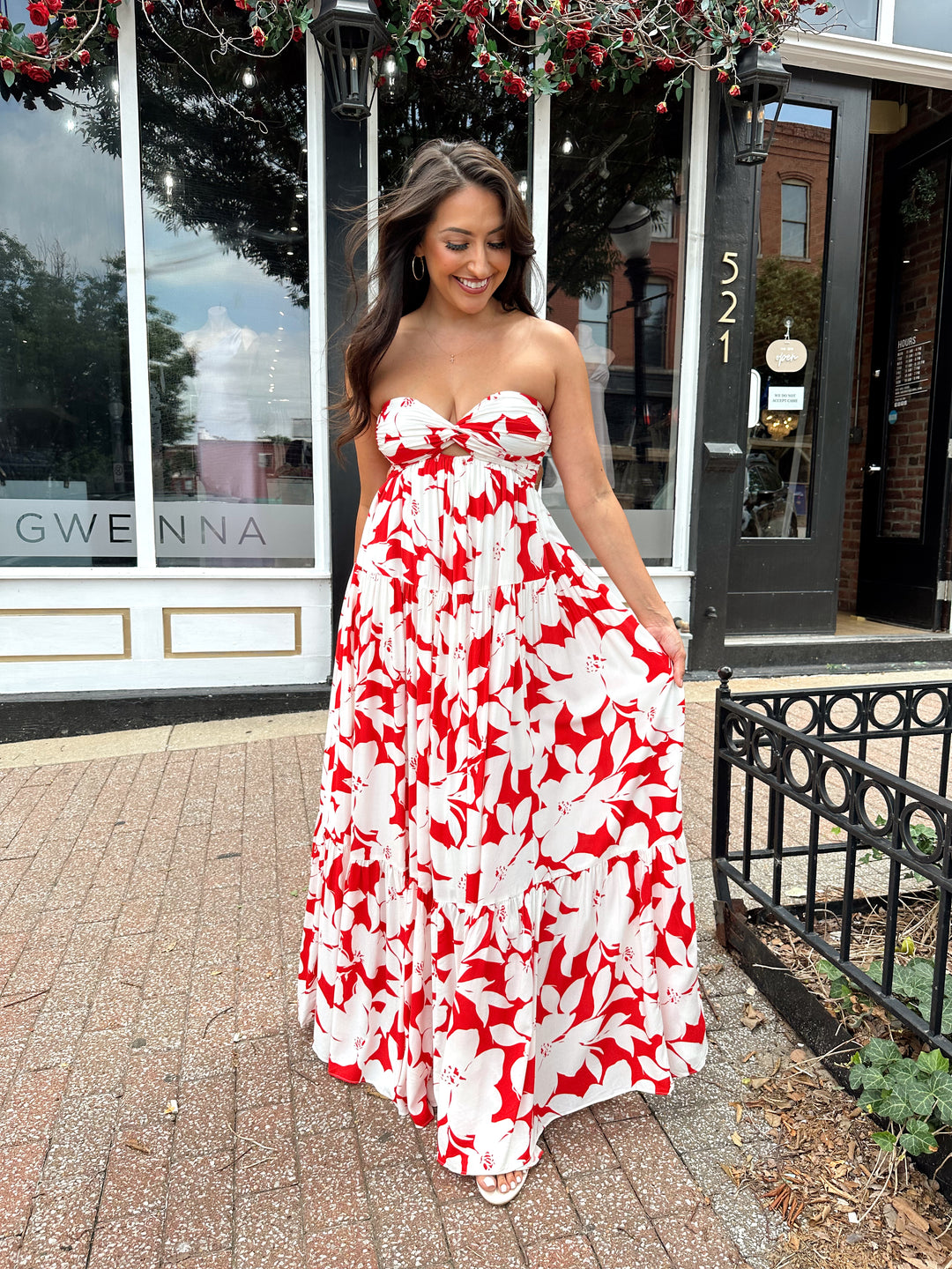 Woman wearing a sleeveless red and white floral mai dress with open back and elastic strap.