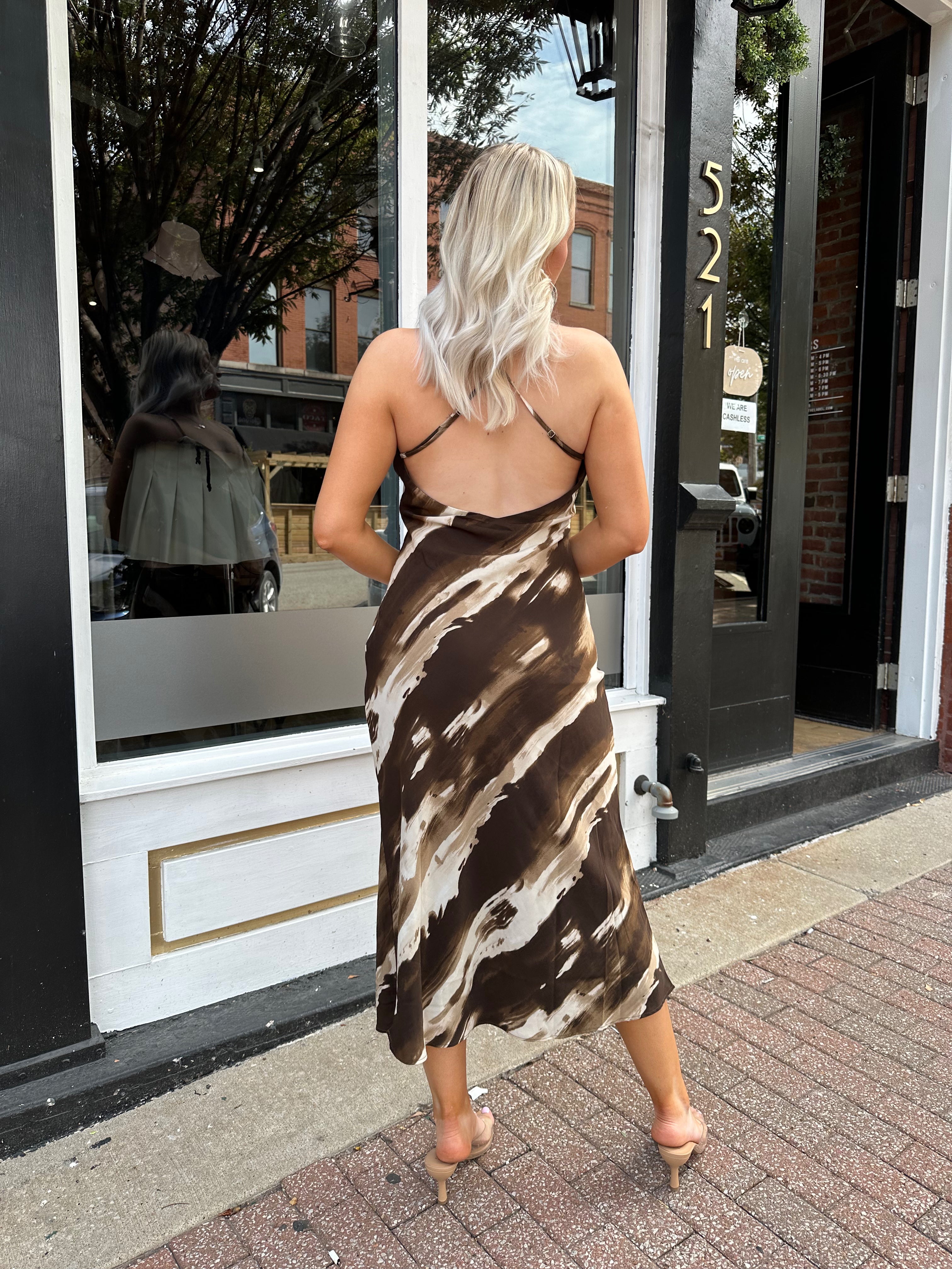 Woman wearing brown abstract pattern midi dress with cross cross back.
