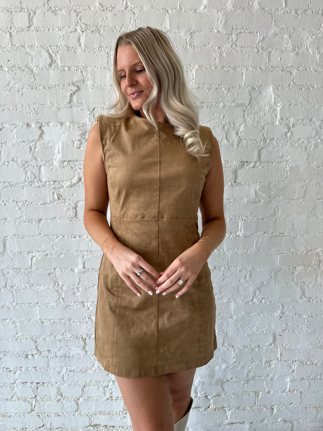 Woman wearing tan suede a-line mini dress with cream knee boots.