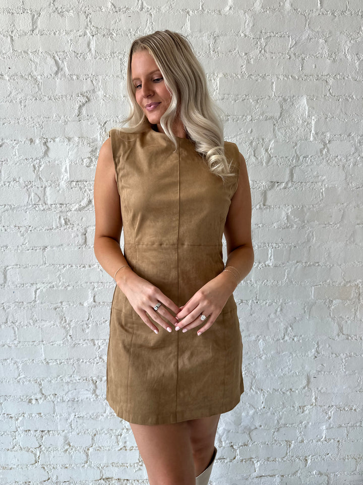 Woman wearing tan suede a-line mini dress with cream knee boots.