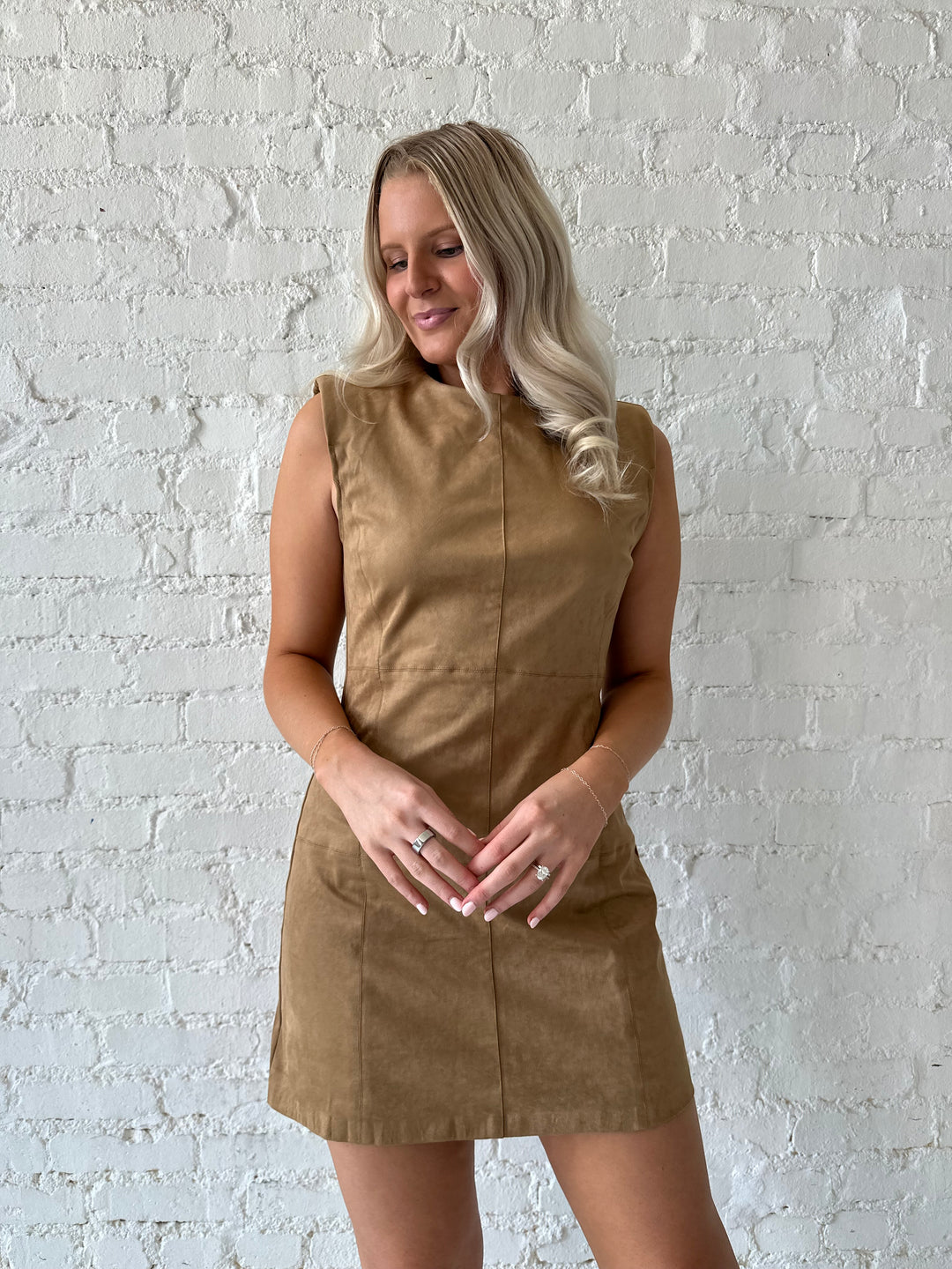 Woman wearing tan suede a-line mini dress with cream knee boots.