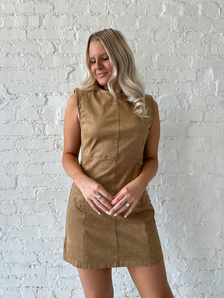 Woman wearing tan suede a-line mini dress with cream knee boots.
