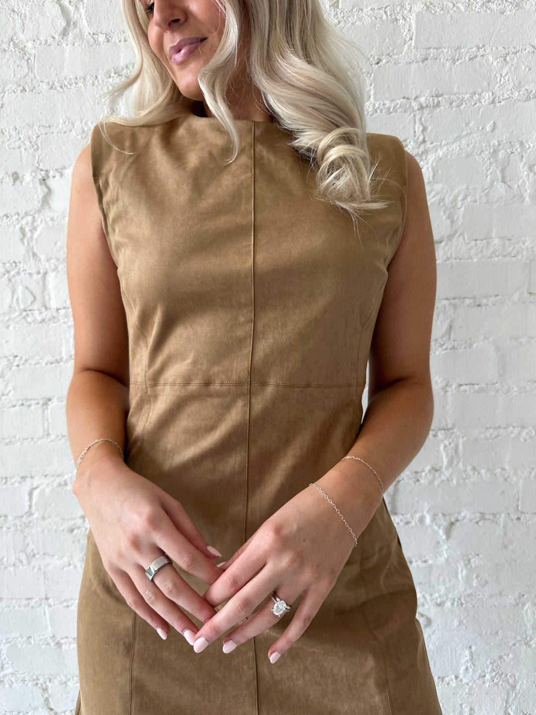 Woman wearing tan suede a-line mini dress with cream knee boots.