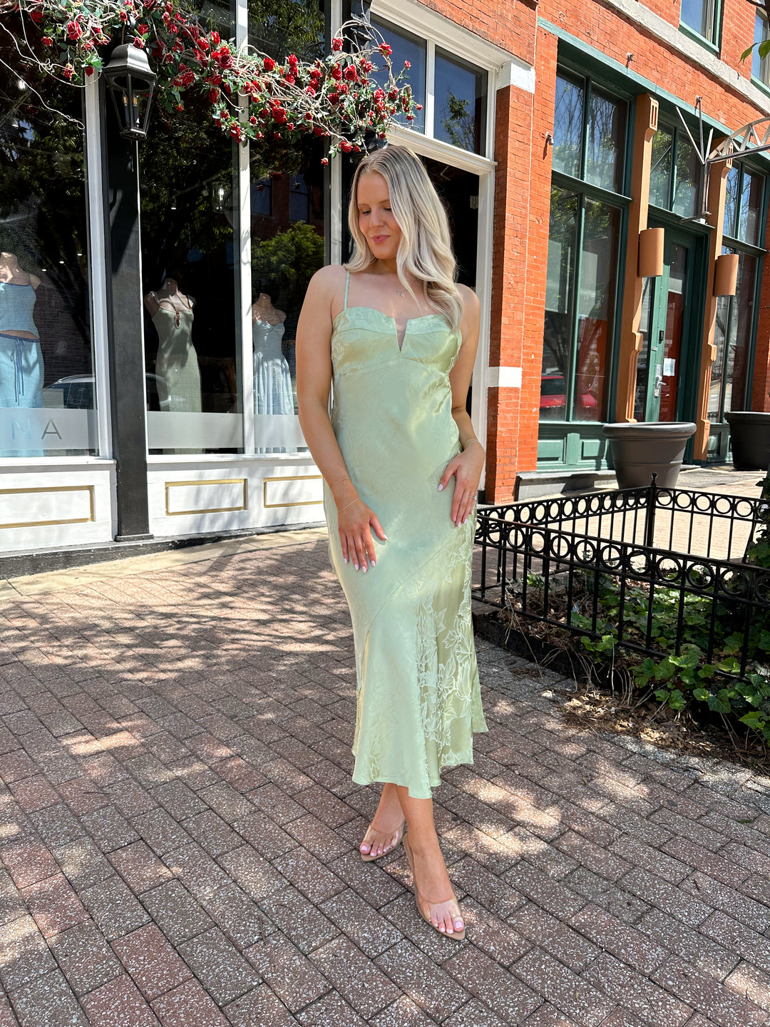 Woman wearing light green jacquard satin maxi dress with adjustable spaghetti straps.