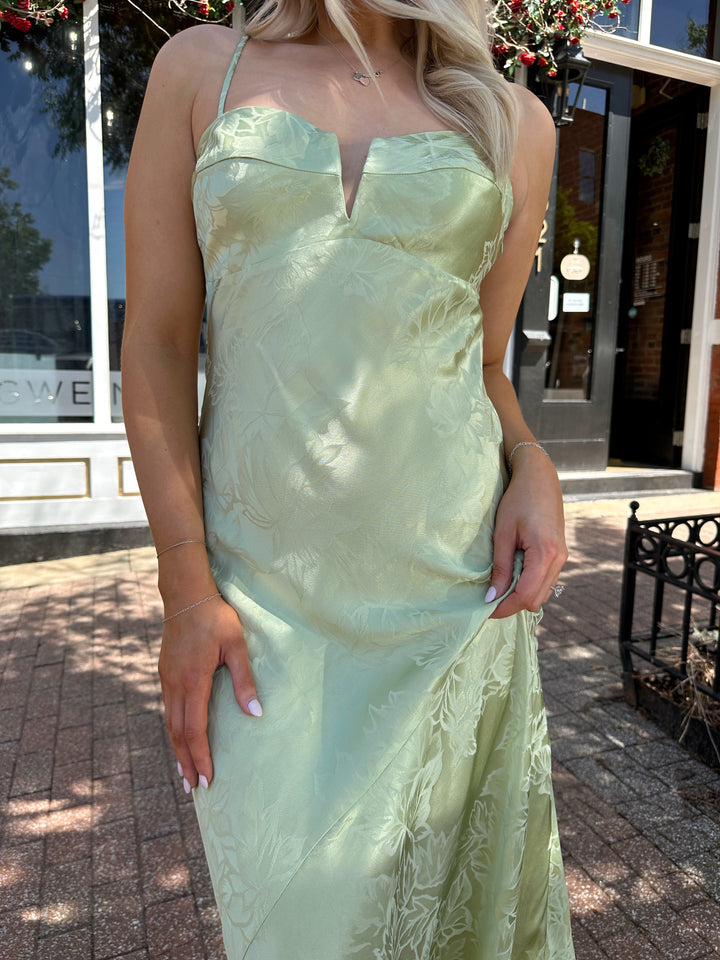 Woman wearing light green jacquard satin maxi dress with adjustable spaghetti straps.
