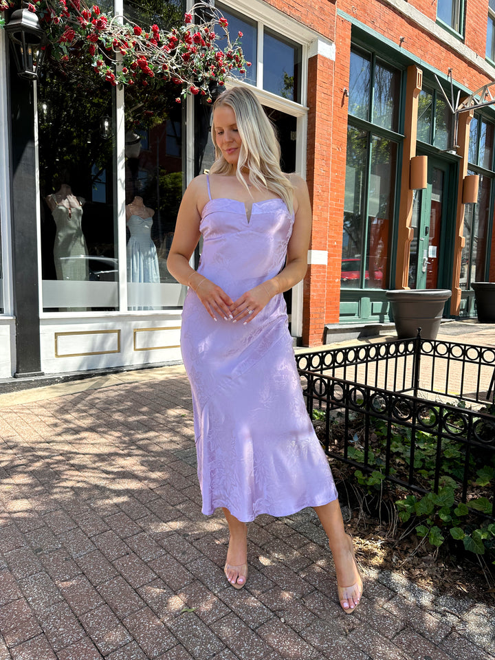 Woman wearing purple jacquard maxi dress with adjustable spaghetti straps.