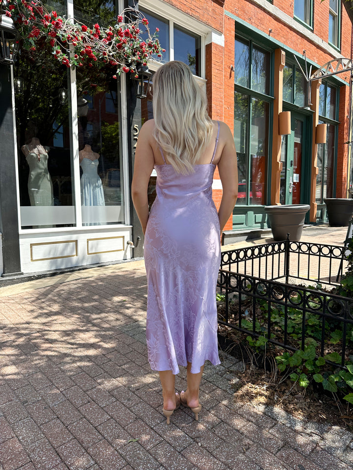 Woman wearing purple jacquard maxi dress with adjustable spaghetti straps.