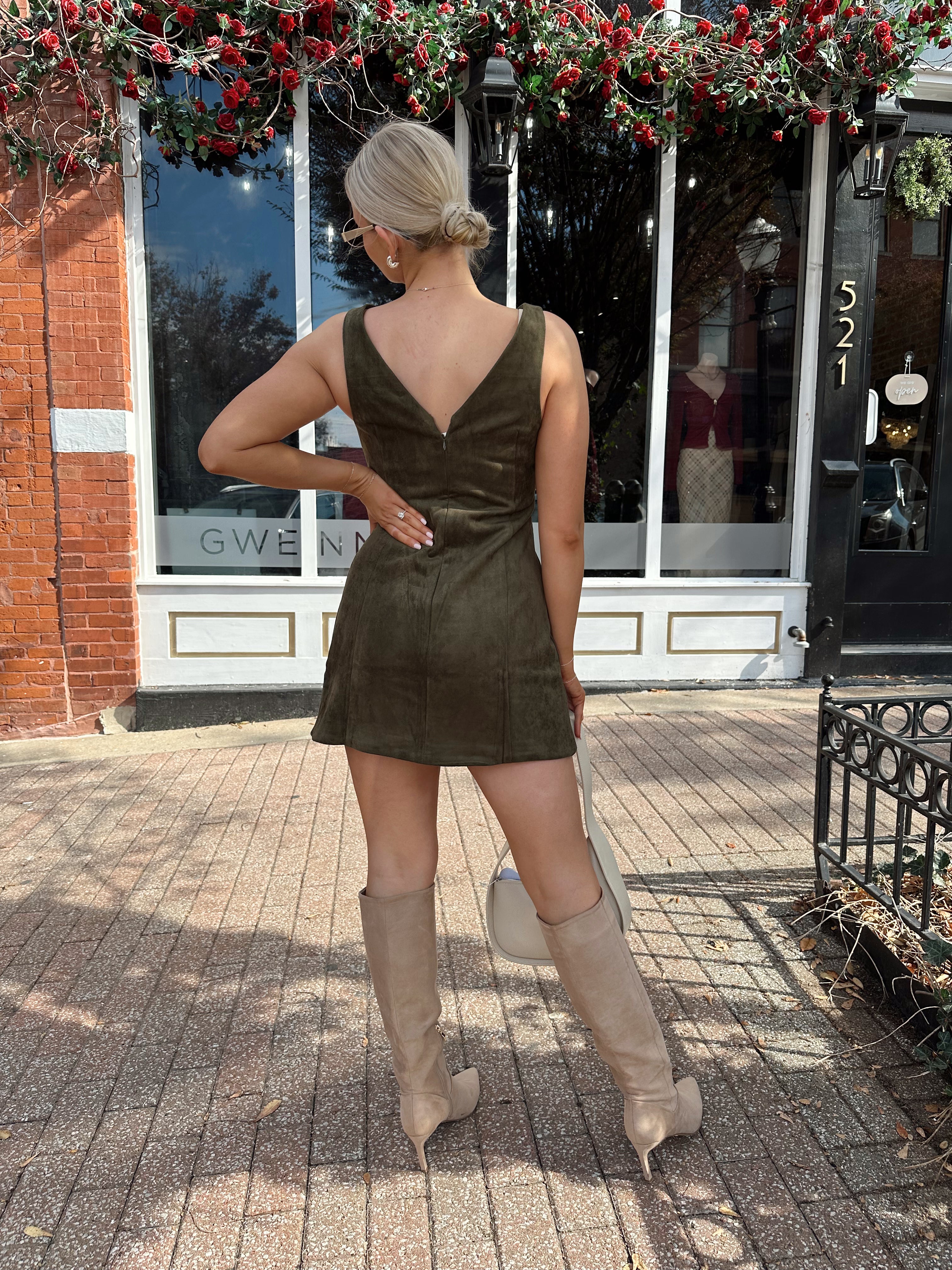 Woman wearing olive green suede mini dress with high neckline and v-back.