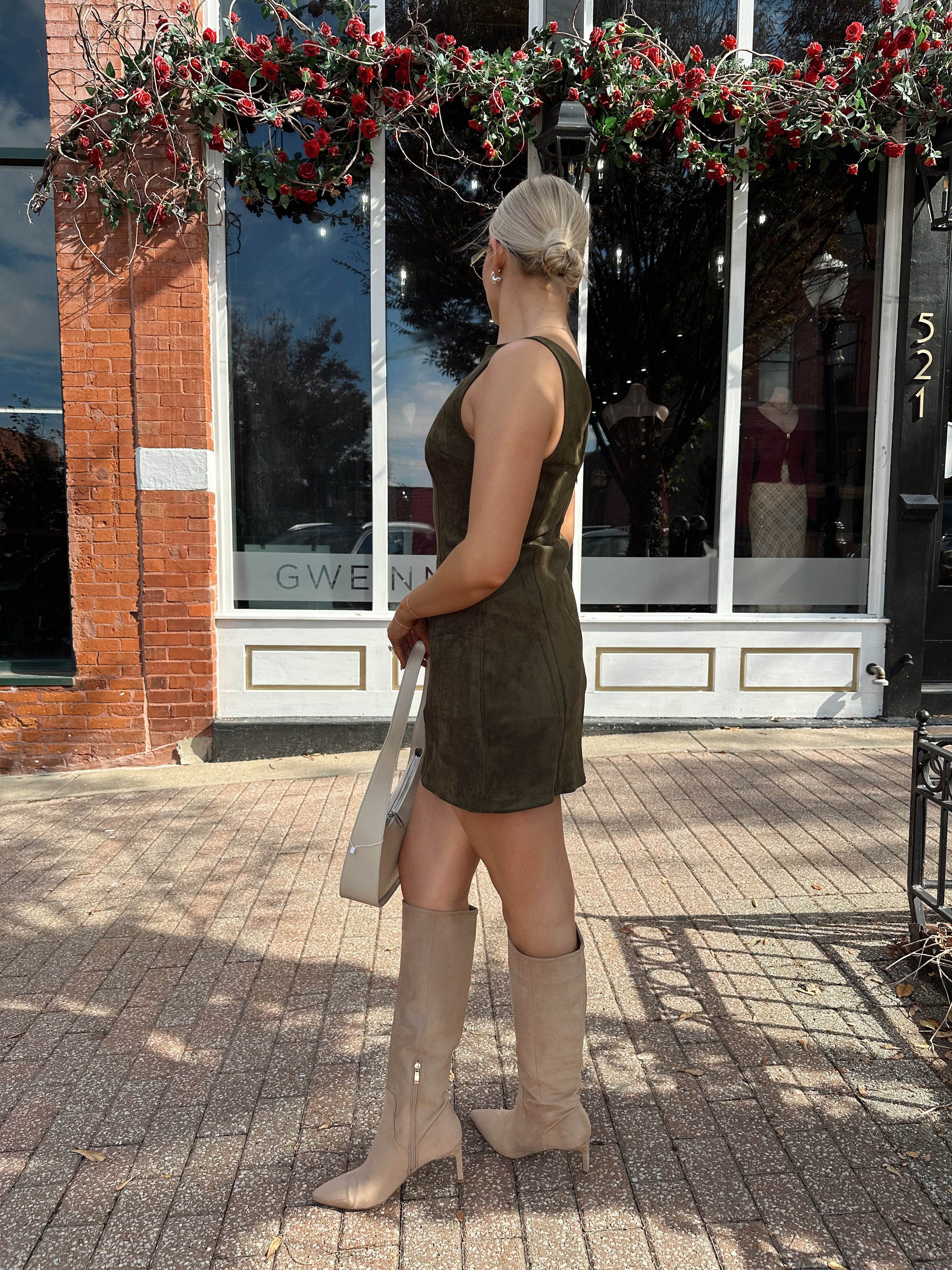 Woman wearing olive green suede mini dress with high neckline and v-back.
