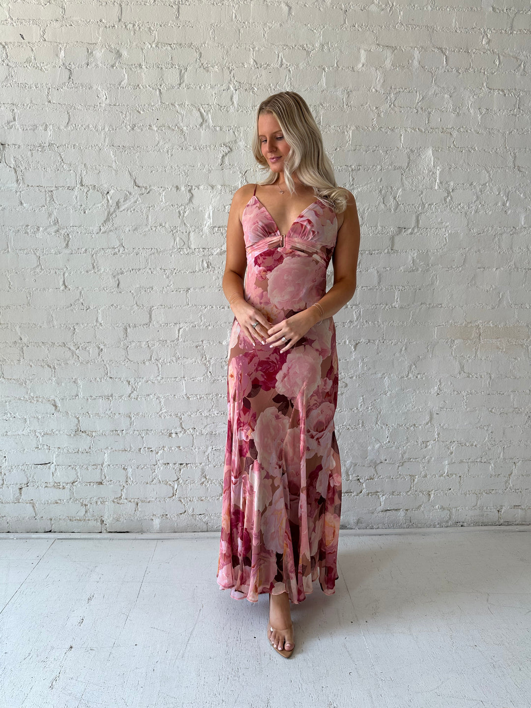 Woman wearing blush floral maxi dress with v-neckline and metal loop detailing. 