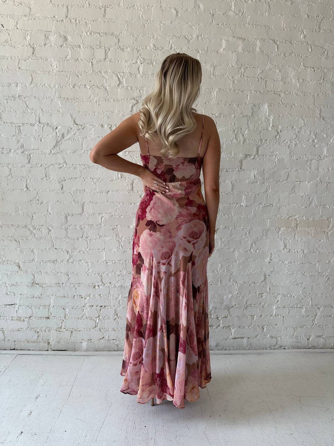 Woman wearing blush floral maxi dress with v-neckline and metal loop detailing. 