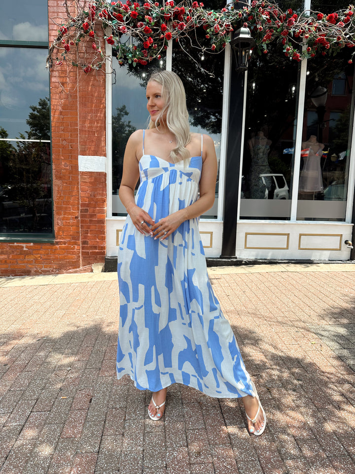 Woman wearing blue and white abstract pattern maxi dress with sweetheart neckline. 