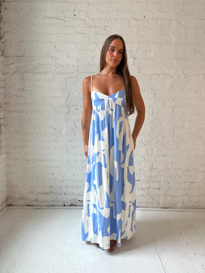 Woman wearing blue and white geometric print maxi dress with sweetheart neckline.