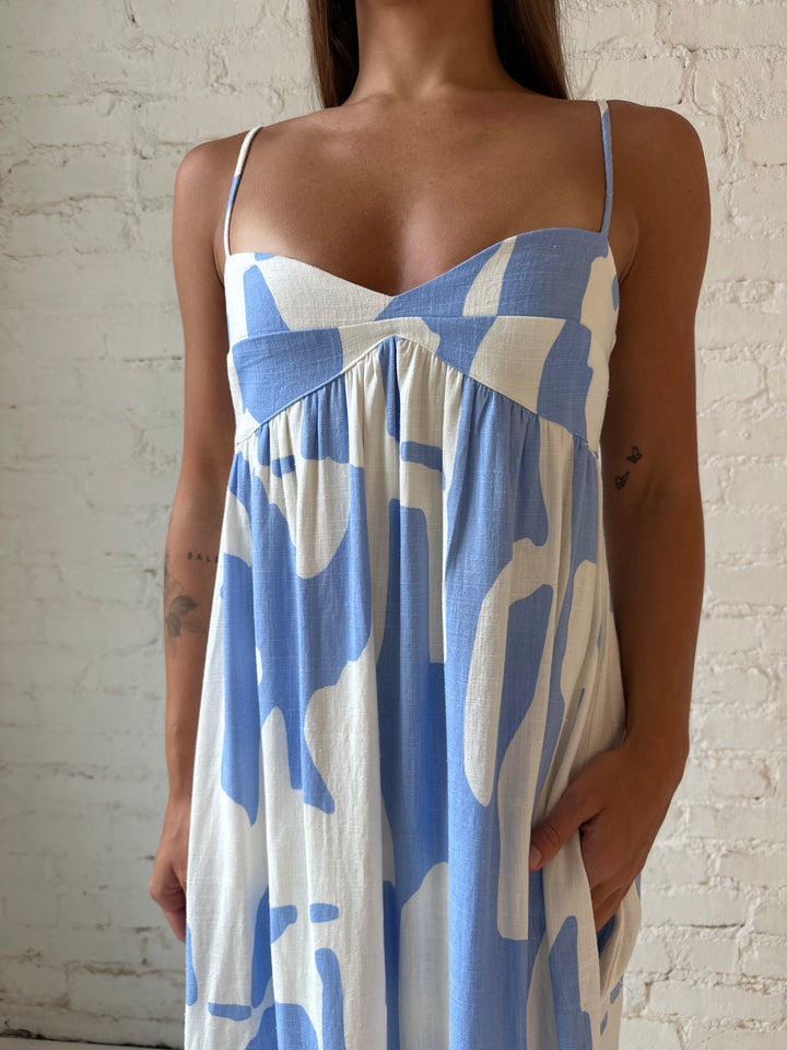 Woman wearing blue and white geometric print maxi dress with sweetheart neckline.