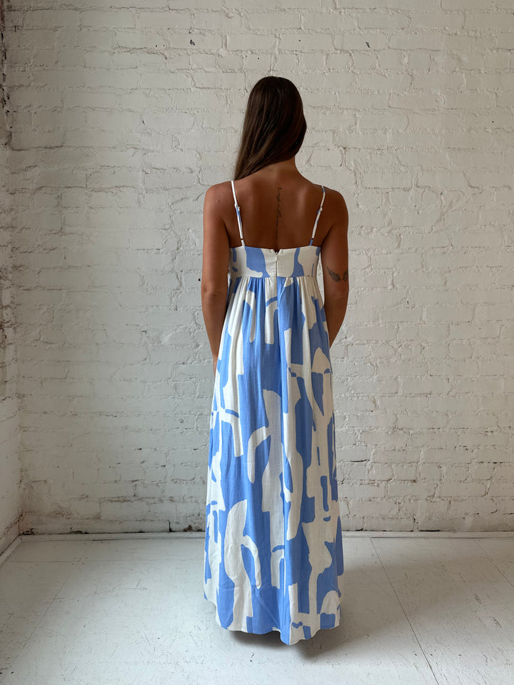 Woman wearing blue and white geometric print maxi dress with sweetheart neckline.