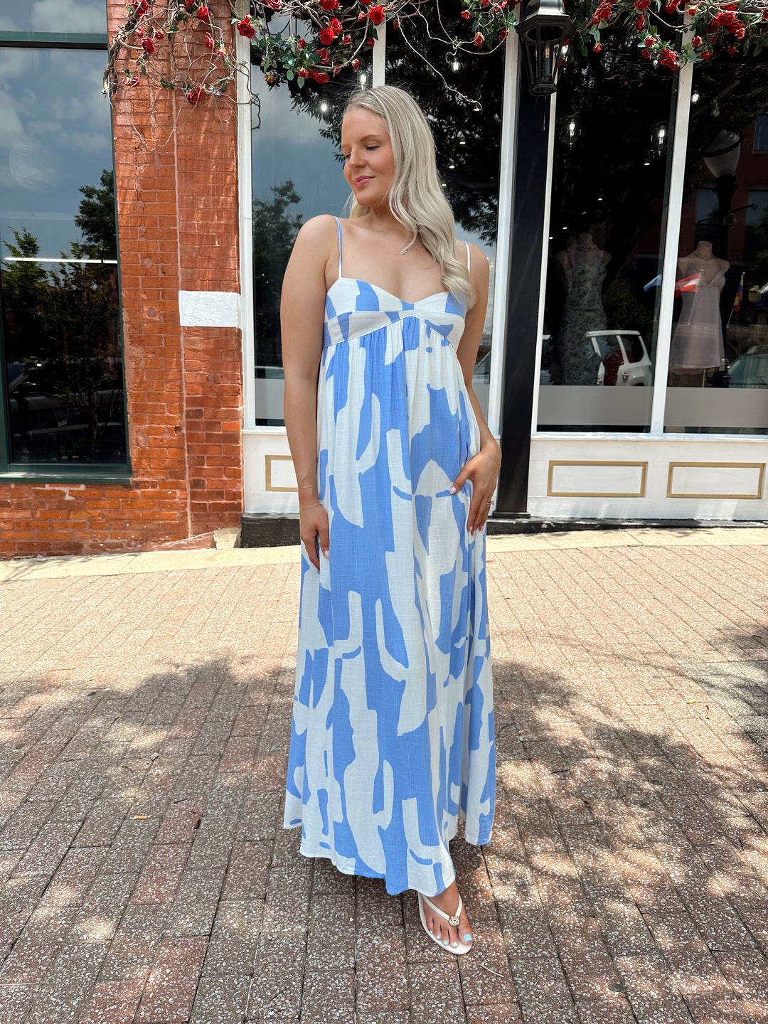 Woman wearing blue and white abstract pattern maxi dress with sweetheart neckline. 