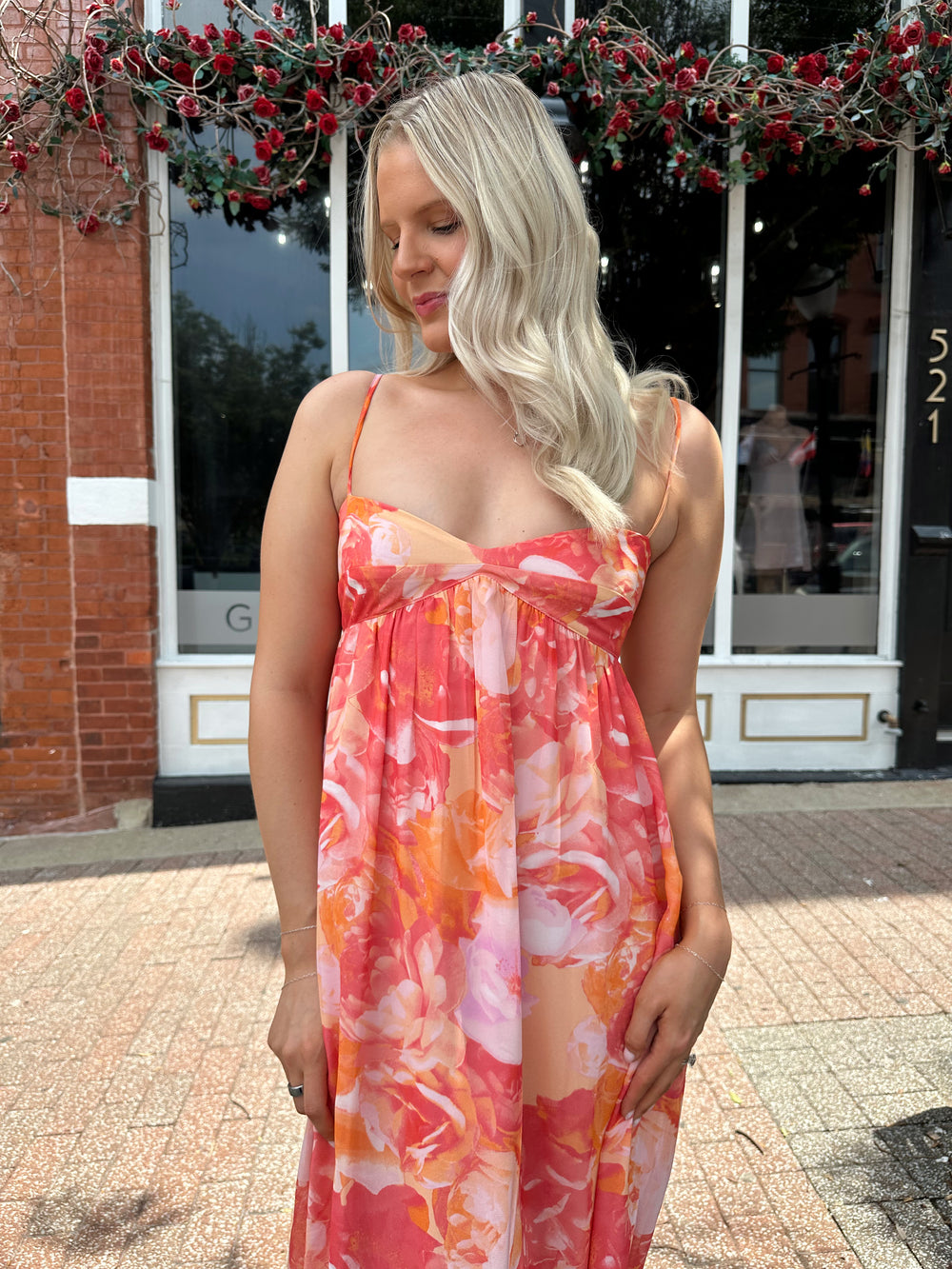 Woman wearing coral floral maxi dress with sweetheart neckline.