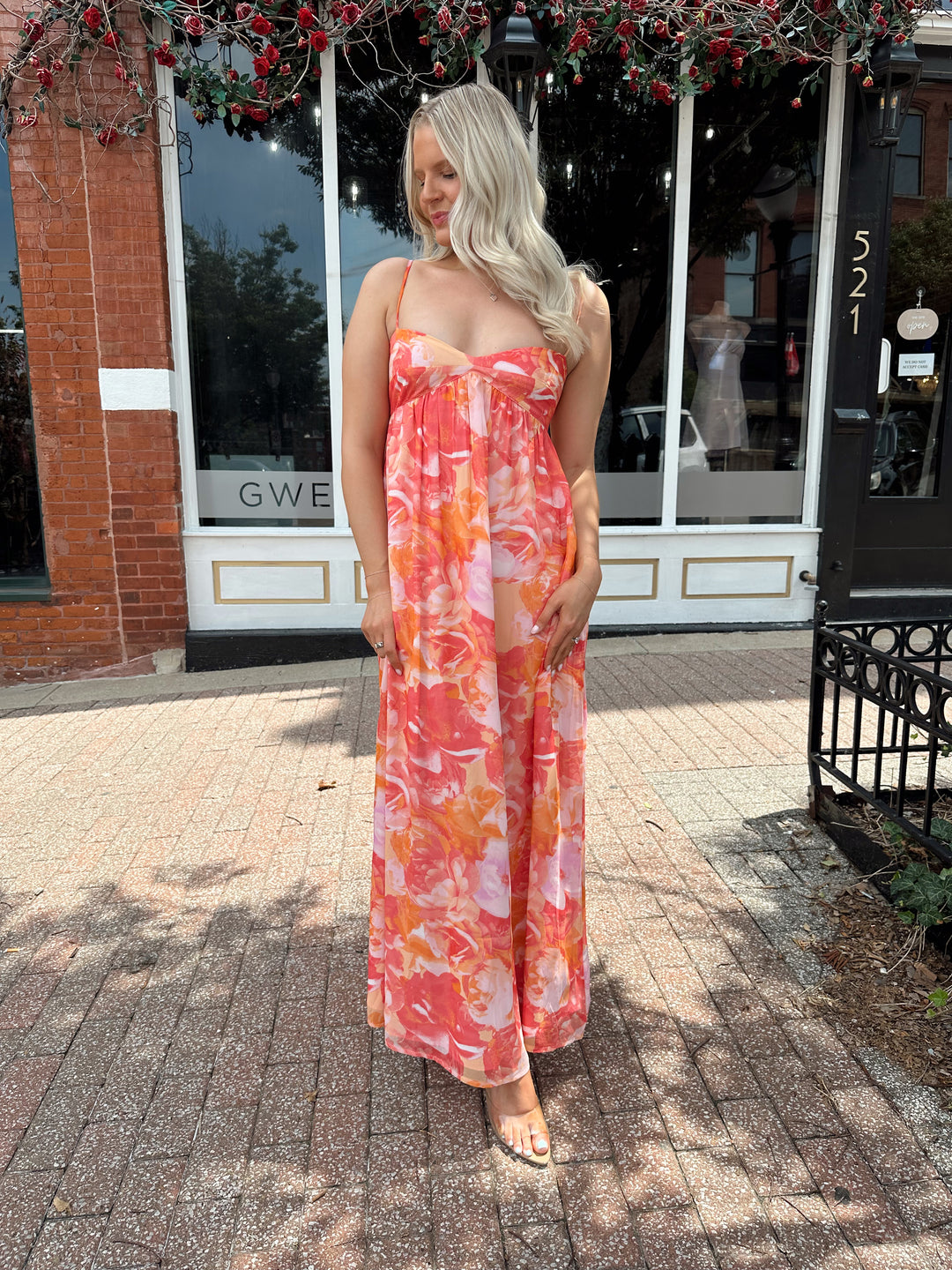 Woman wearing coral floral maxi dress with sweetheart neckline.