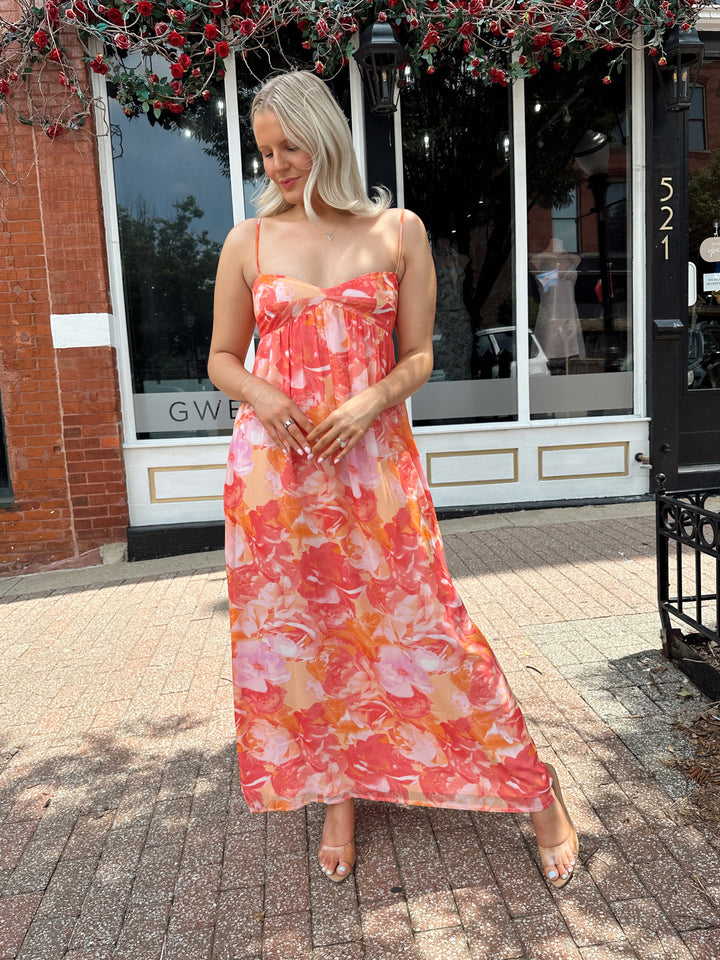 Woman wearing coral floral maxi dress with sweetheart neckline.