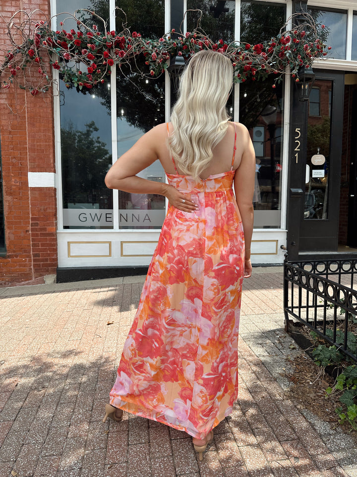 Woman wearing coral floral maxi dress with sweetheart neckline.