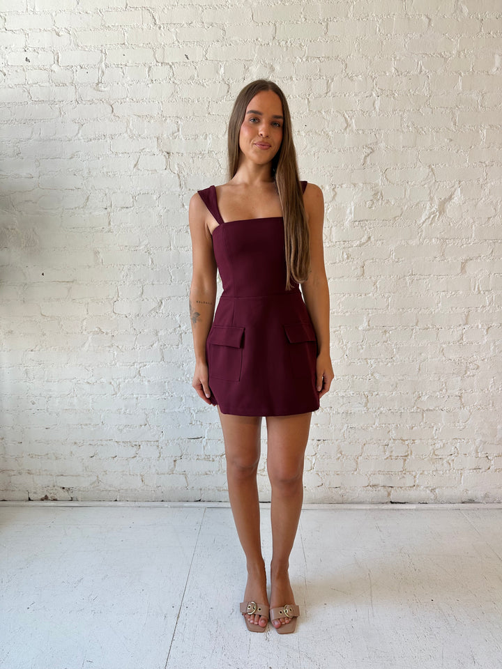 Woman wearing burgundy tailored mini dress with built in shorts. 