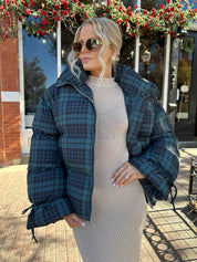 Woman wearing navy plaid puffer coat with oversized fit and draw string cuffs.