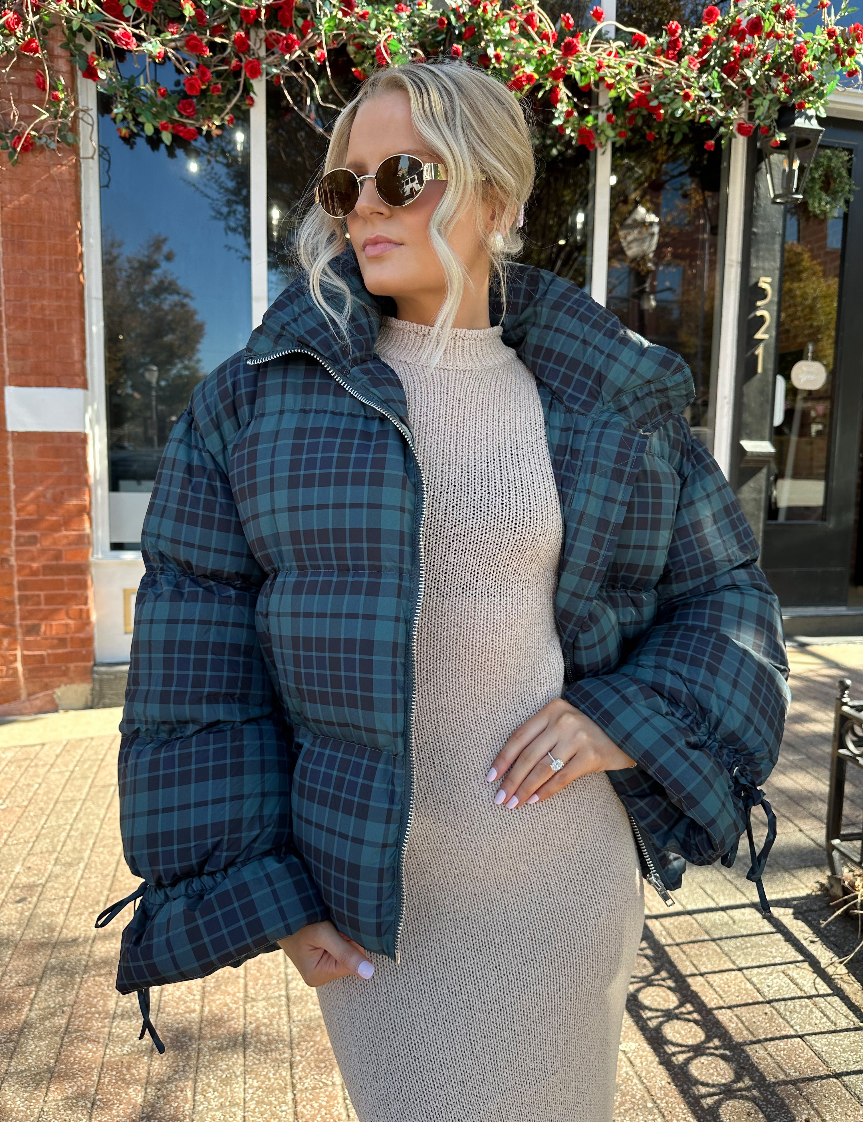 Woman wearing navy plaid puffer coat with oversized fit and draw string cuffs.