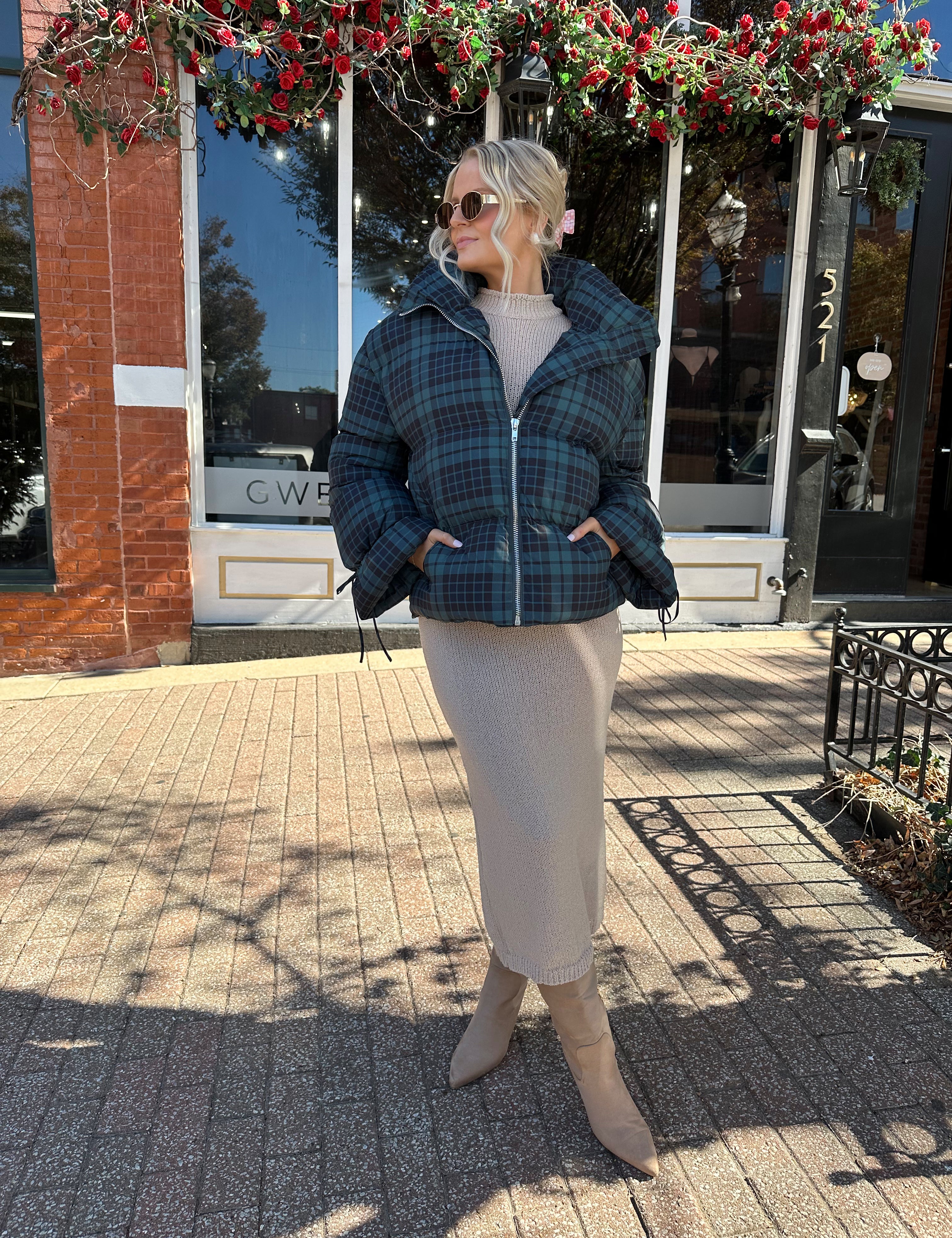 Woman wearing navy plaid puffer coat with oversized fit and draw string cuffs.