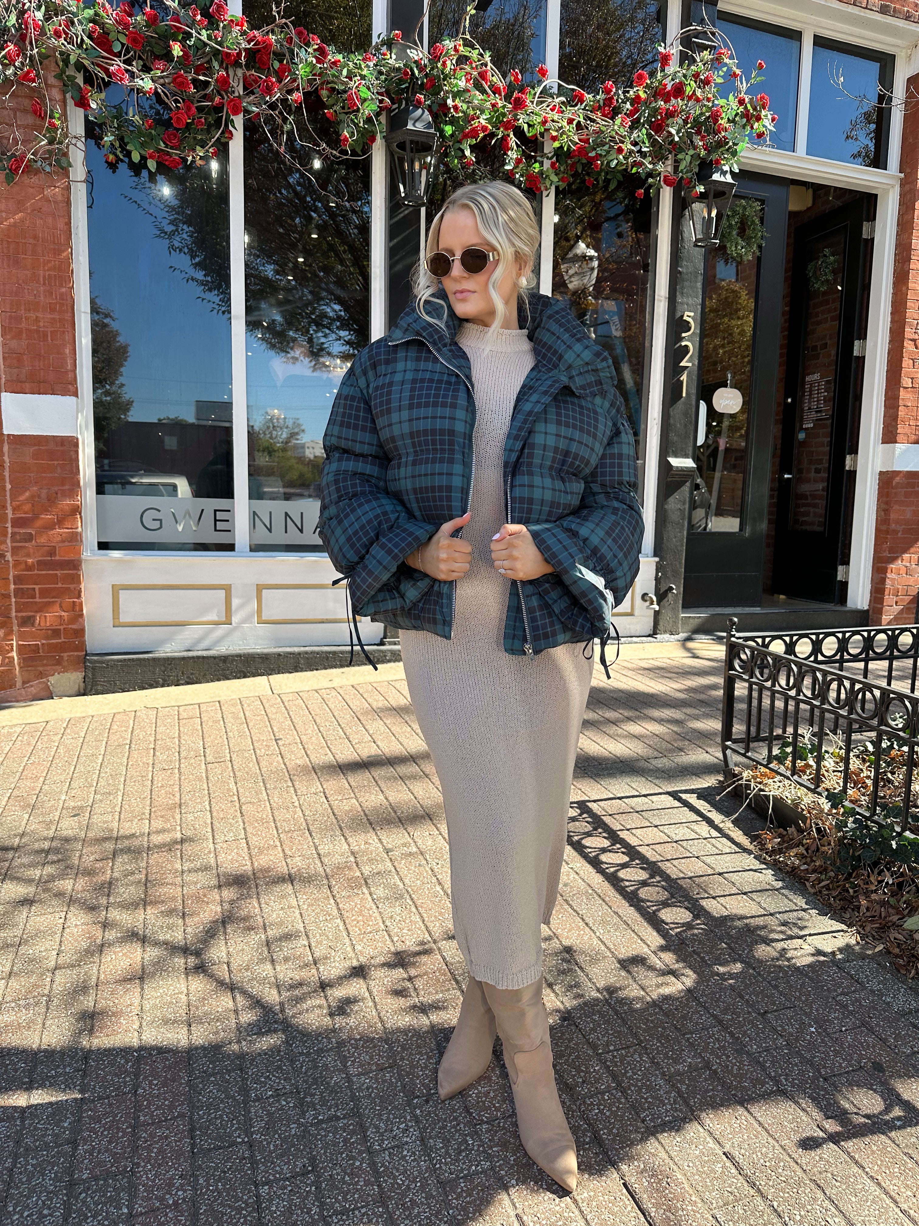 Woman wearing navy plaid puffer coat with oversized fit and draw string cuffs.