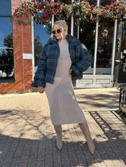 Woman wearing navy plaid puffer coat with oversized fit and draw string cuffs.