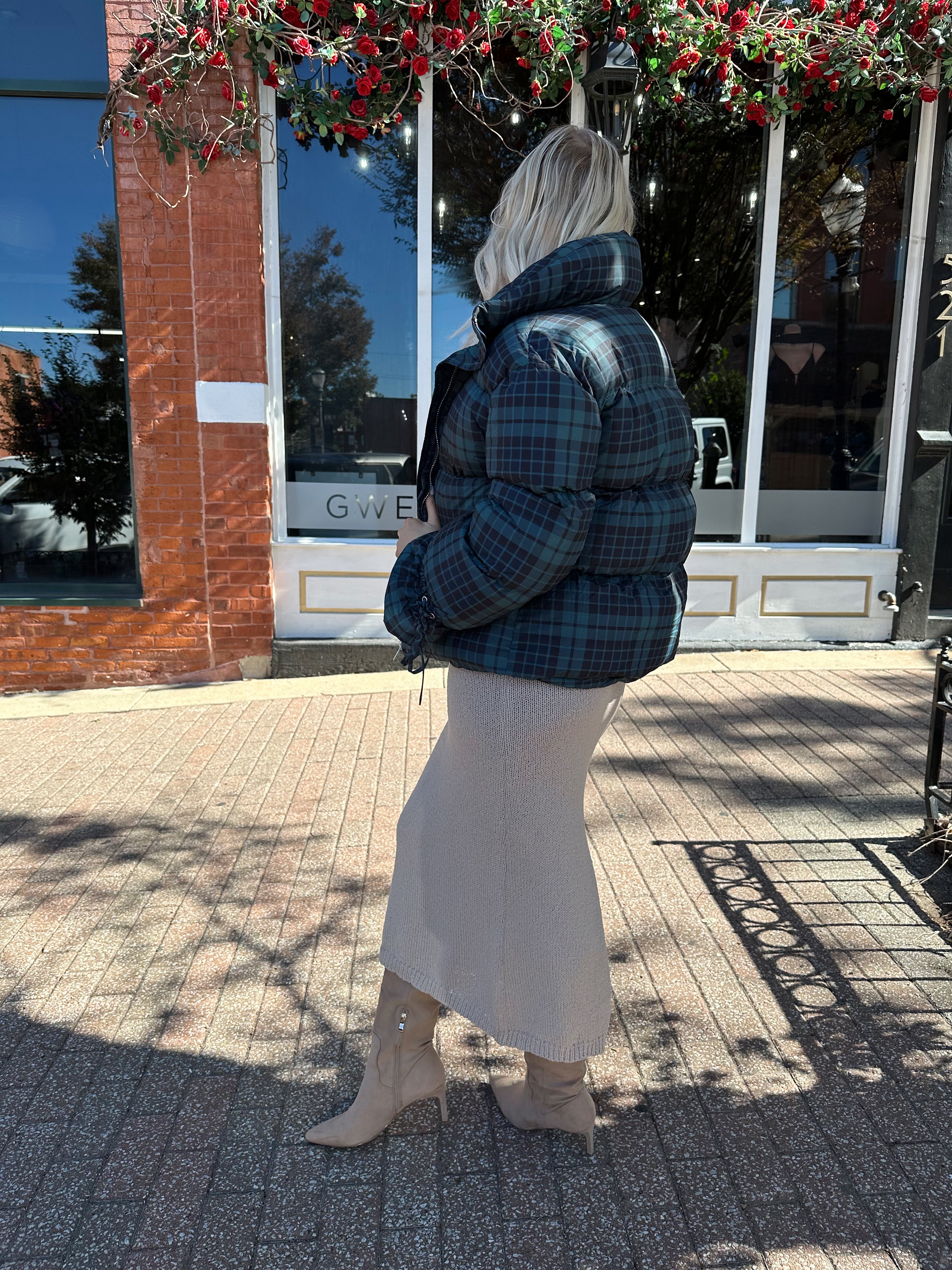 Woman wearing navy plaid puffer coat with oversized fit and draw string cuffs.