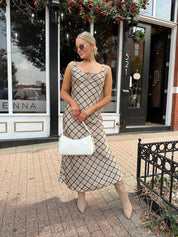 Woman wearing brown plaid satin maxi dress with keyhole tie. 