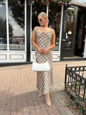 Woman wearing brown plaid satin maxi dress with keyhole tie. 