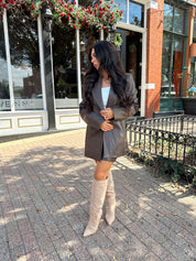 Woman wearing brown vegan leather oversized blazer. 