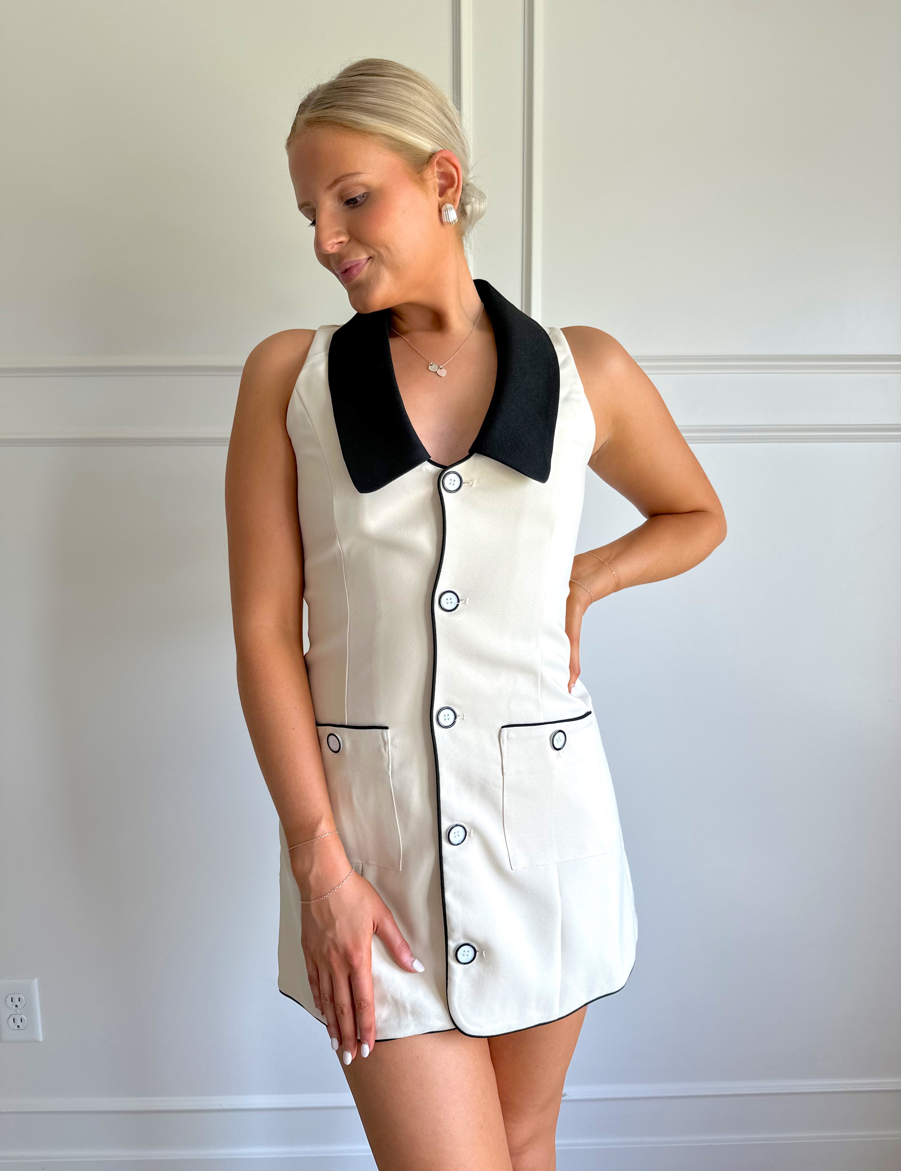 Cream a-line tailored mini dress with black collar and tie.