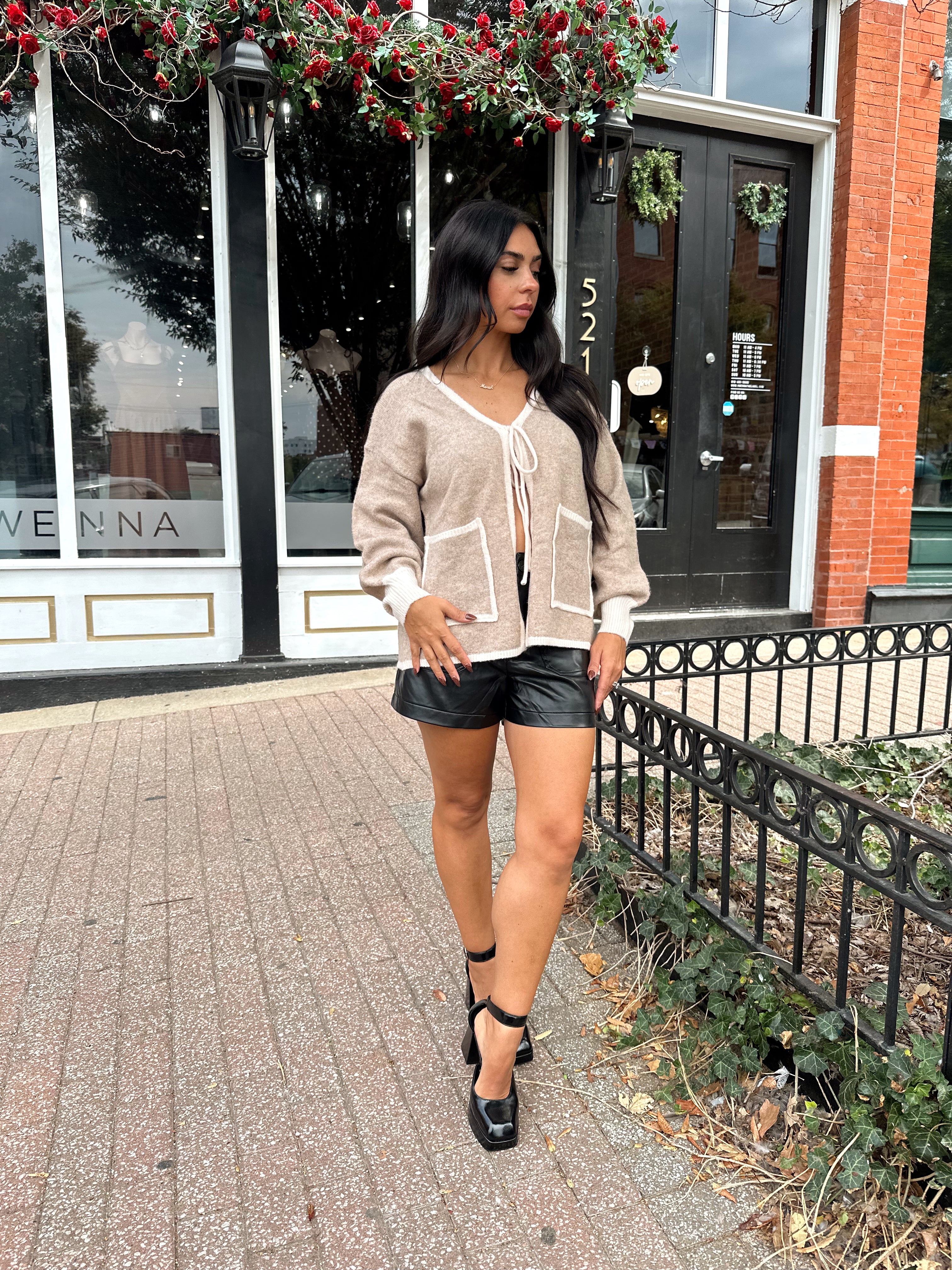 Woman wearing taupe tie front cardigan with functional pockets and contrast trim detail.