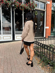 Woman wearing taupe tie front cardigan with functional pockets and contrast trim detail.