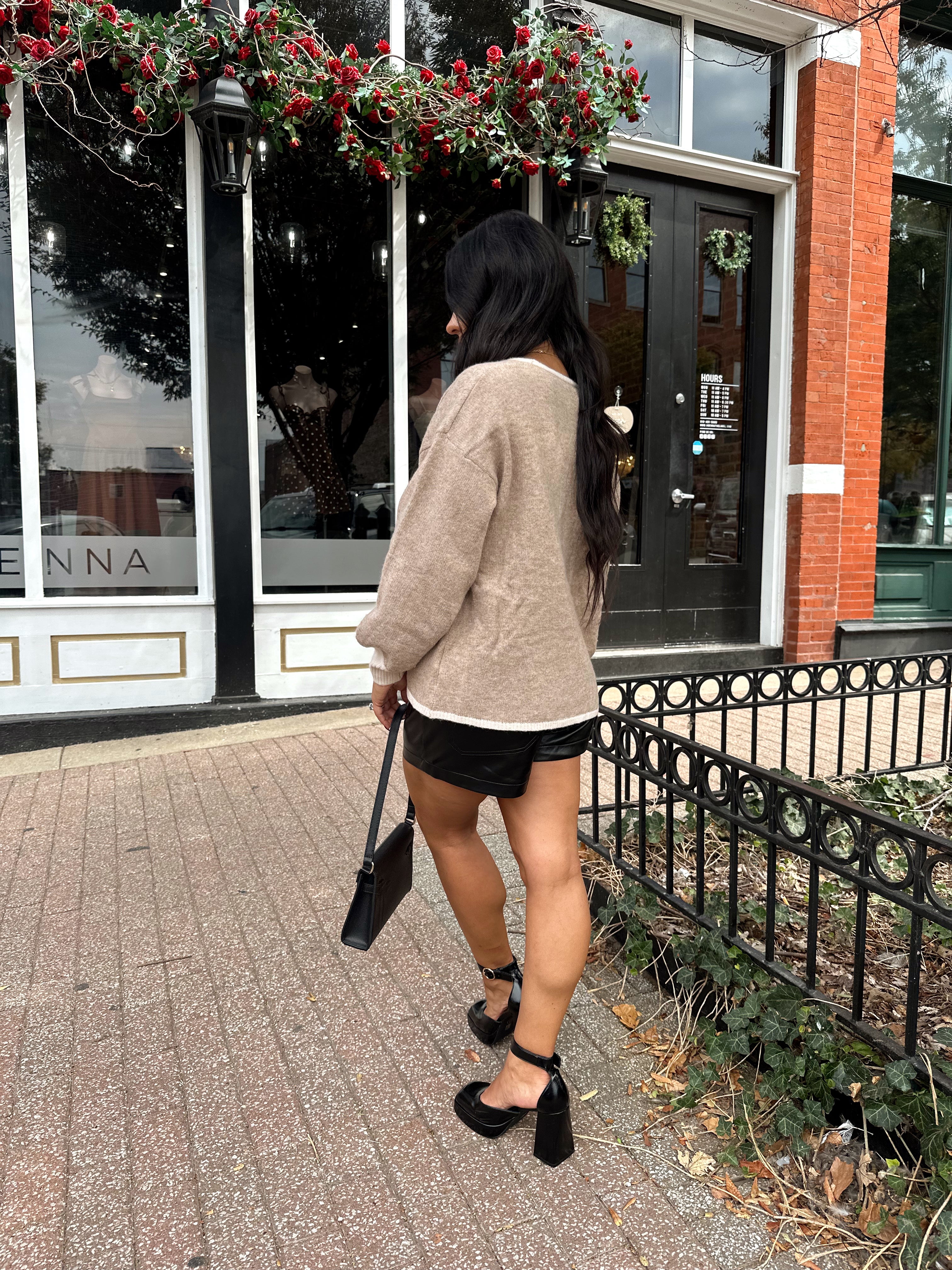 Woman wearing taupe tie front cardigan with functional pockets and contrast trim detail.