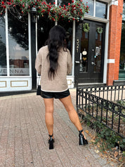 Woman wearing taupe tie front cardigan with functional pockets and contrast trim detail.