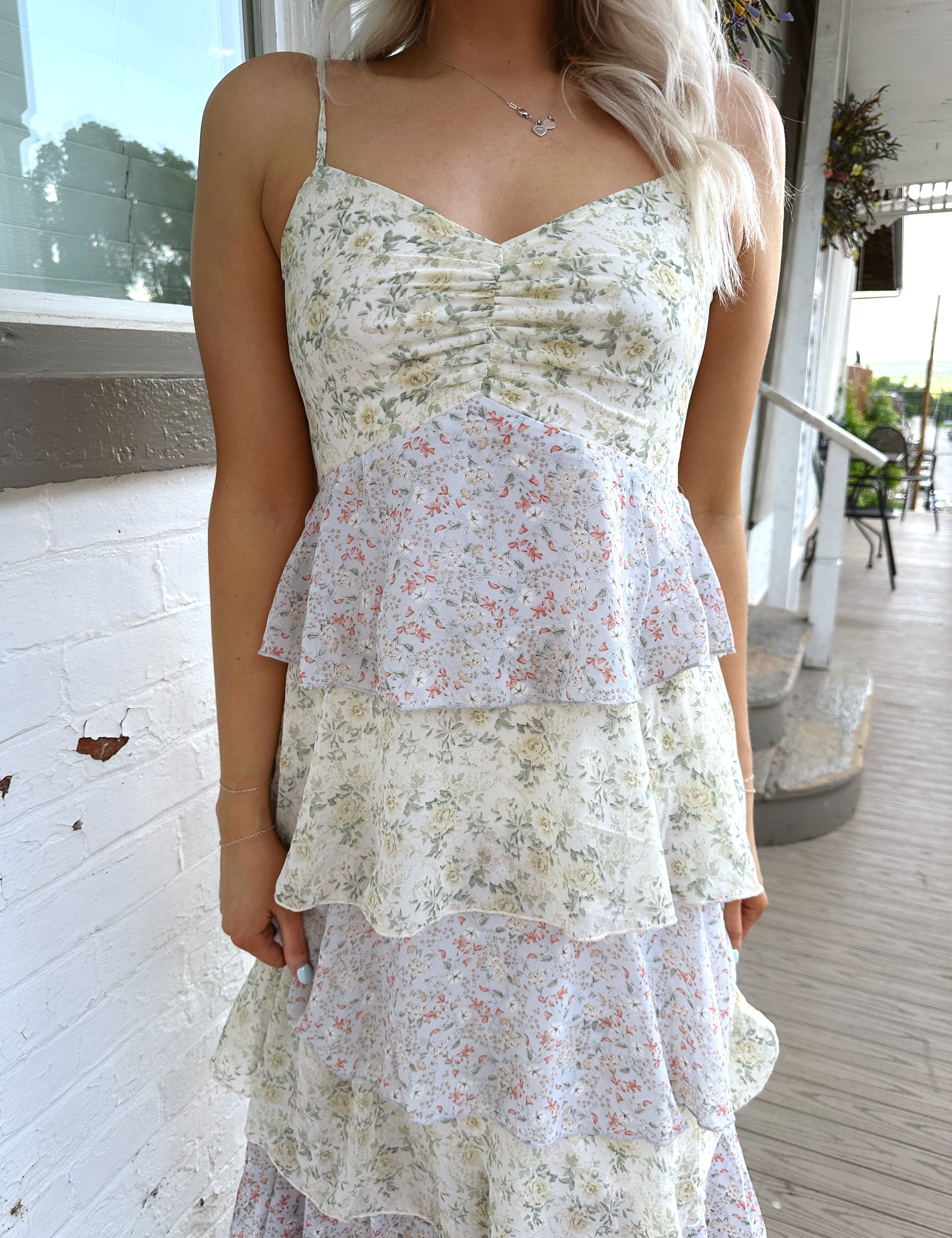 Woman wearing a purple and green tiered floral maxi dress with spaghetti straps on a porch