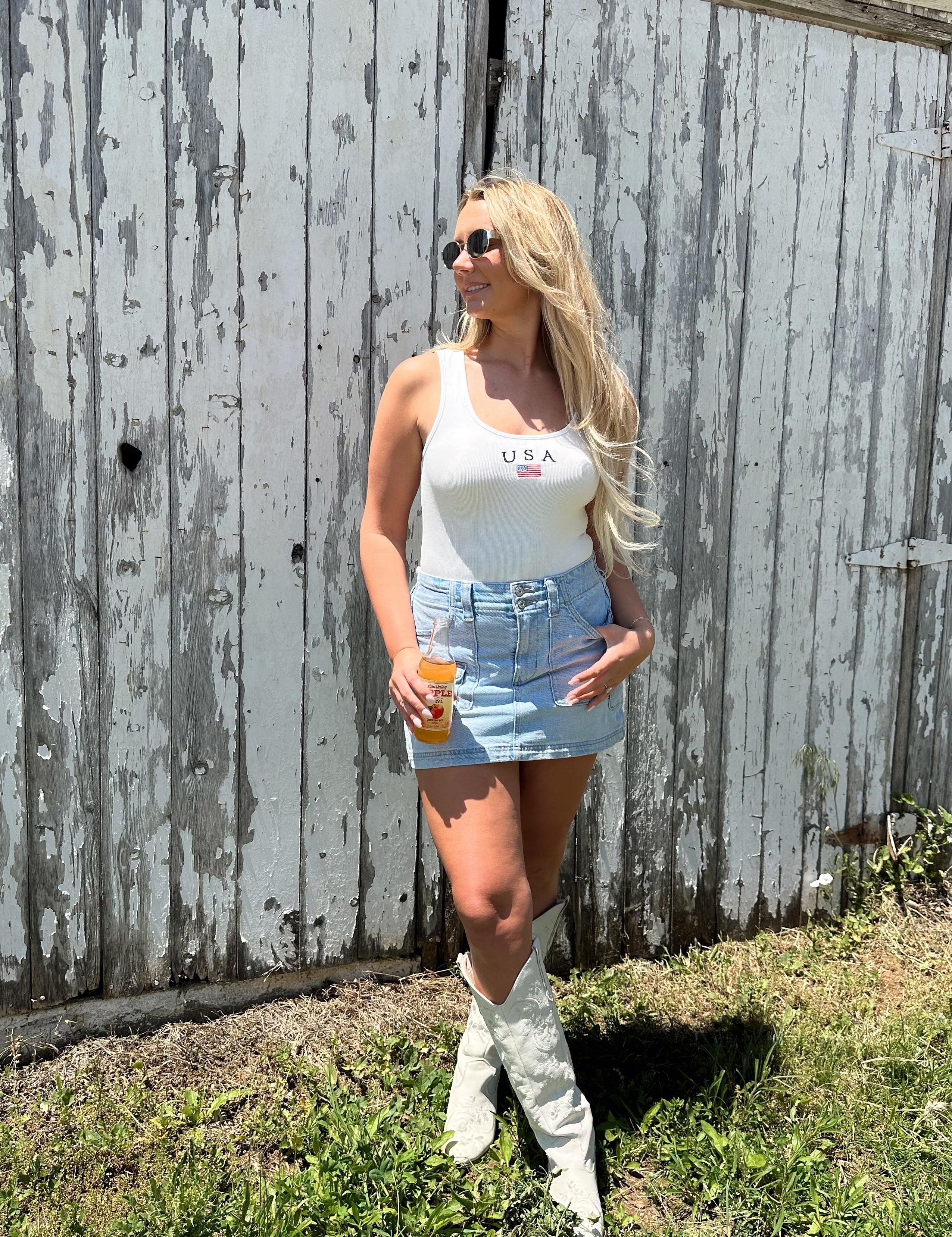 Woman in a white sleeveless bodysuit with “USA” and small flag embroidered on the chest