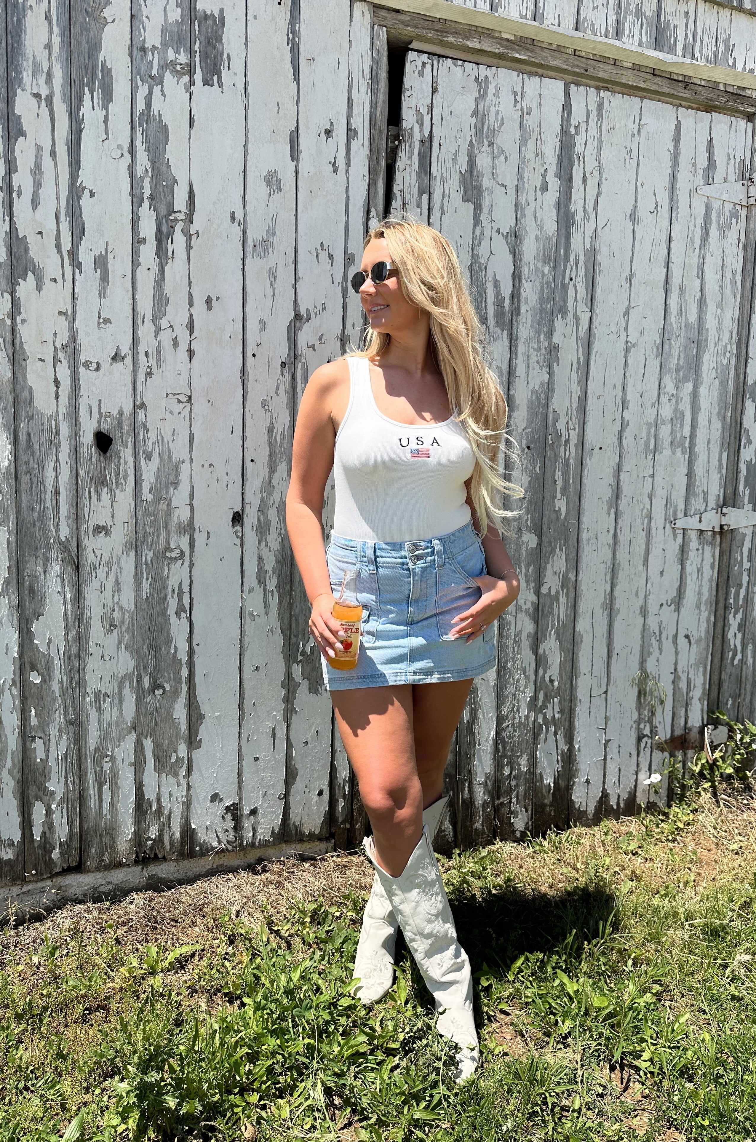 Woman in a white sleeveless bodysuit with “USA” and small flag embroidered on the chest