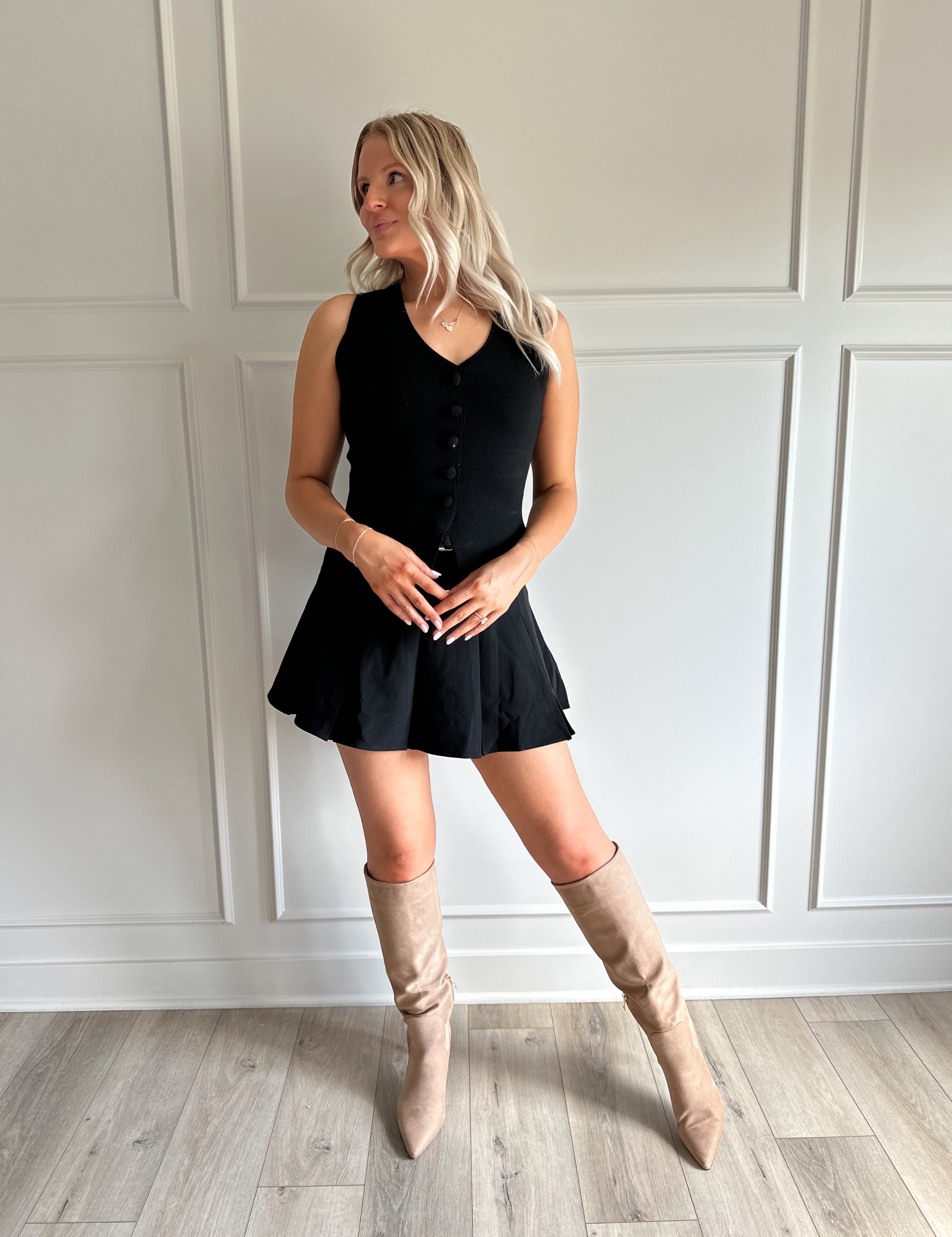 Woman wearing black tailored vest top with button detailing. 