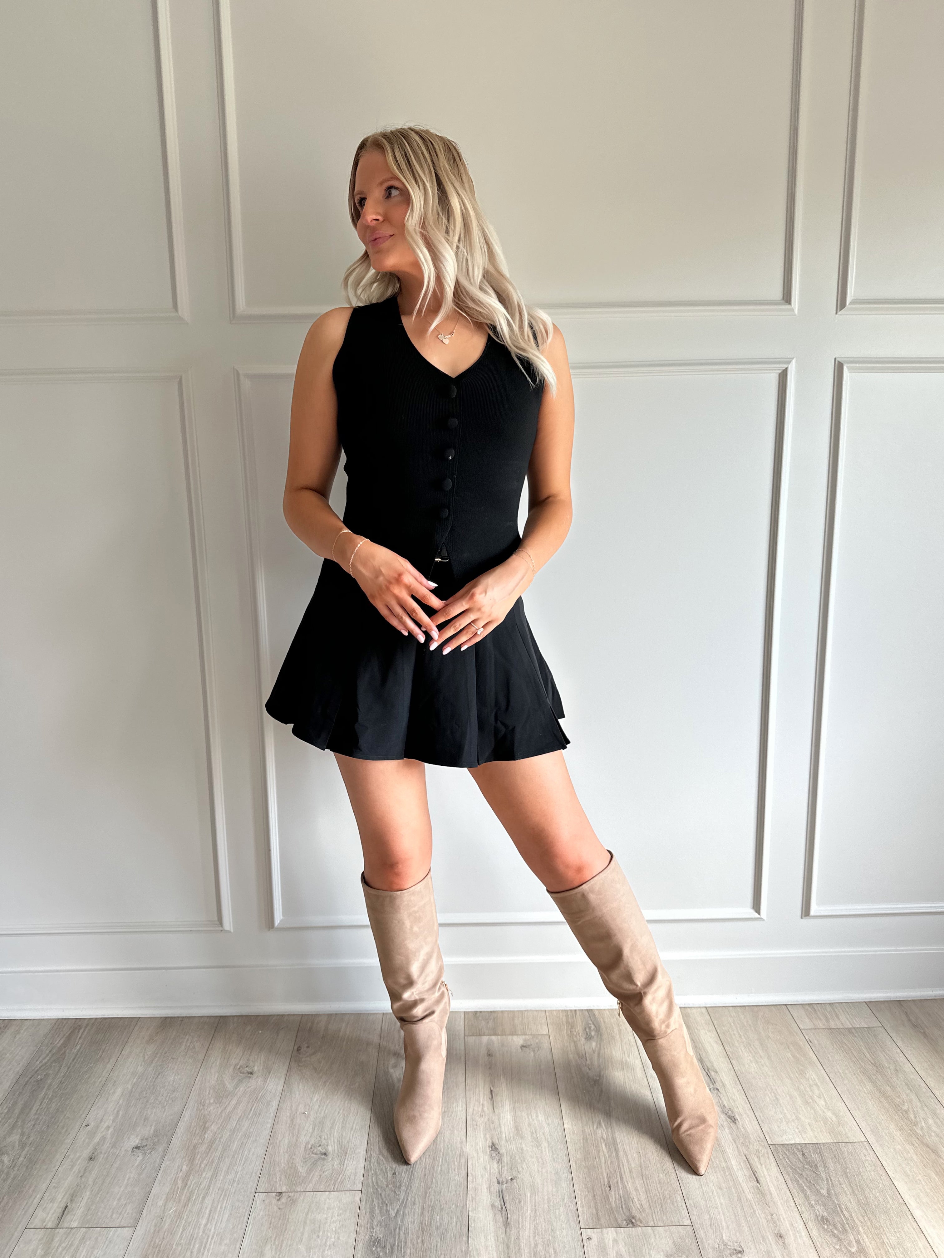 Woman wearing black tailored vest top with button detailing. 