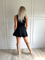 Woman wearing black tailored vest top with button detailing. 
